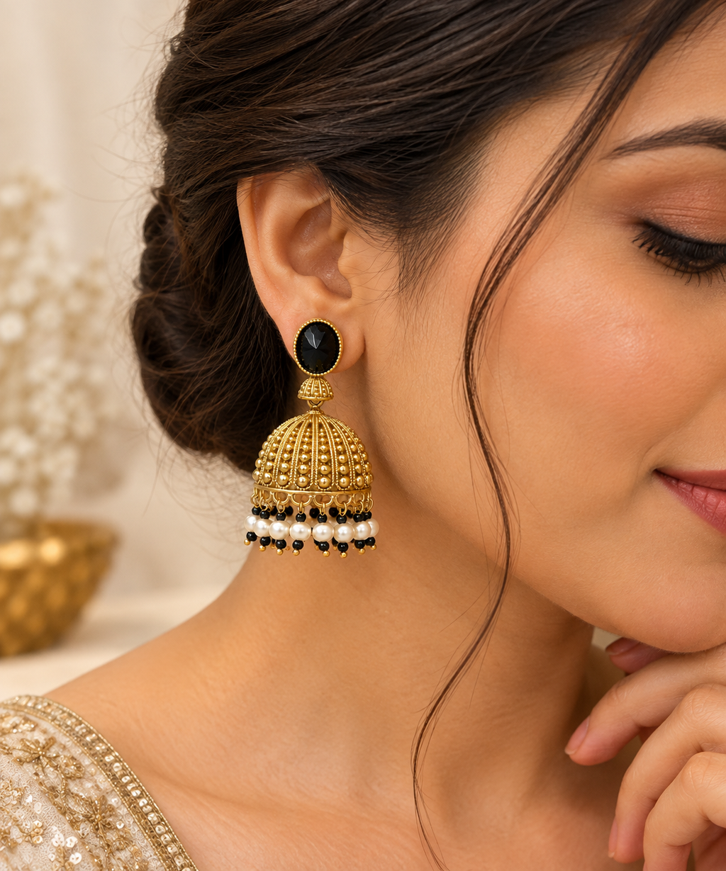 Indian model wearing black and gold Jhumka earrings with ornate domes and hanging bead accents