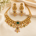 Traditional gold necklace with matching long earrings on a cream display bust