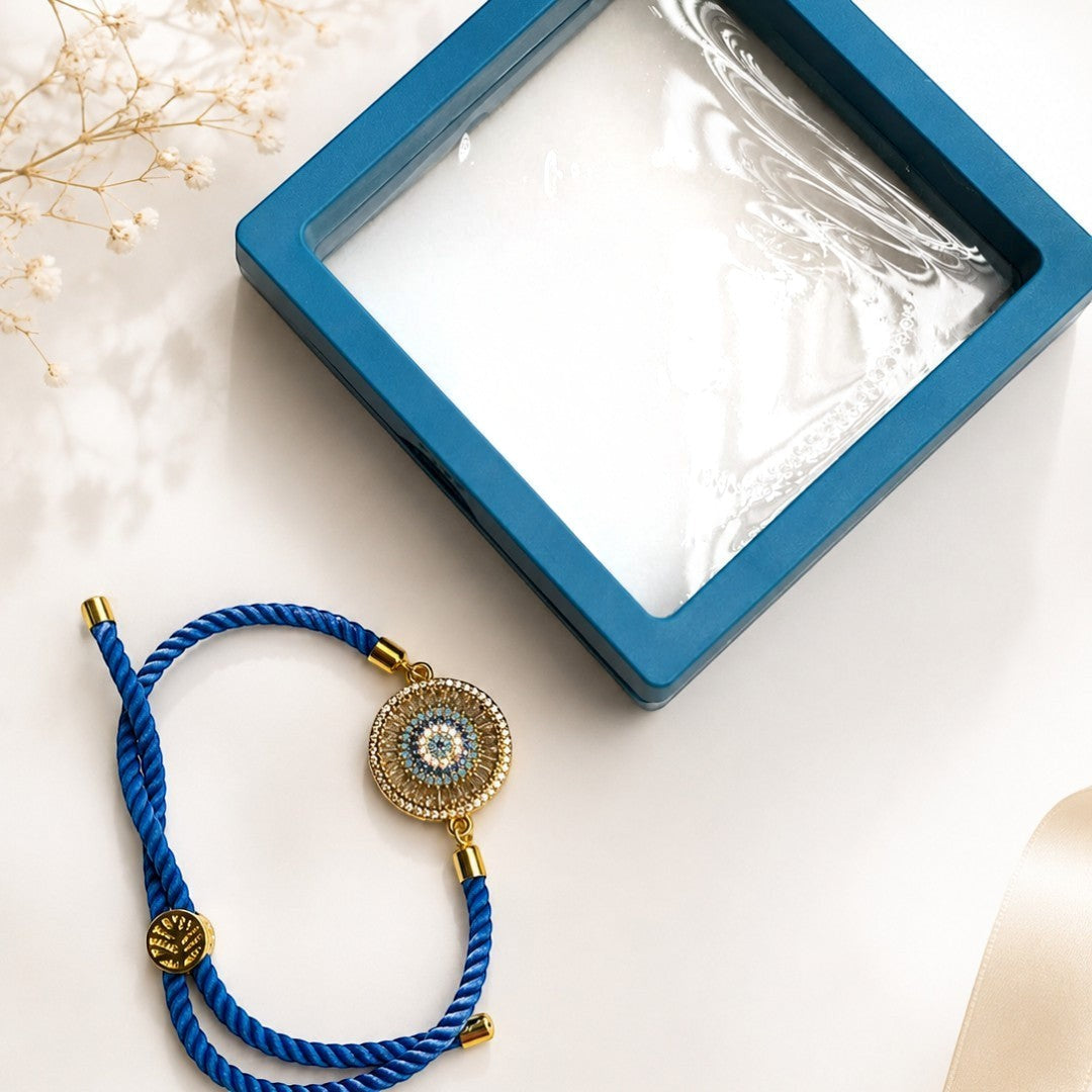 Kallos Jewellery premium blue braided bracelet Rakhi featuring a gold-tone circular pendant with AD zircon stones.