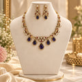 Purple and gold AD jewellery set with ornate necklace and matching long earrings on a warm ivory background