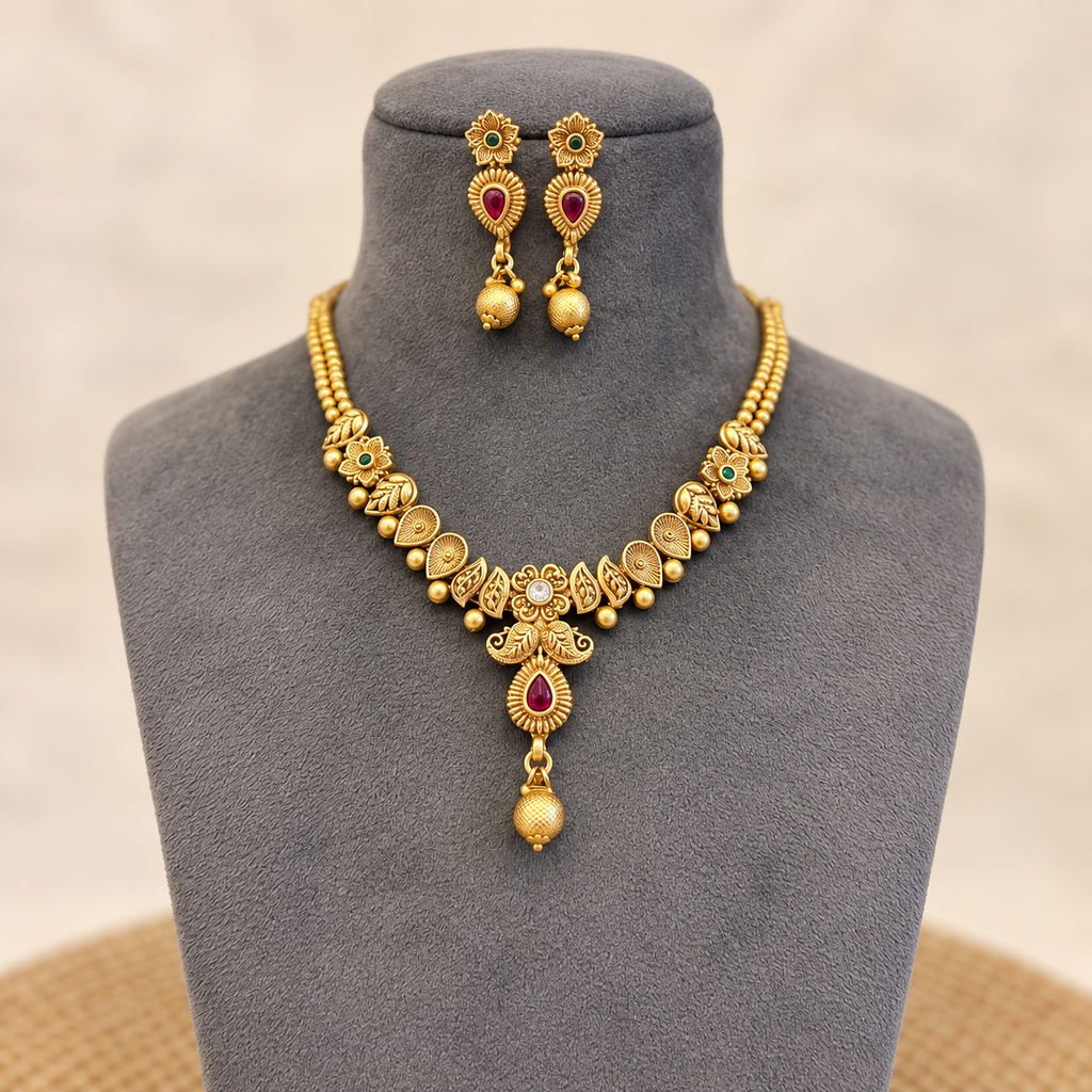 Natural-looking gold-tone necklace set with matching earrings presented on a grey jewellery mannequin